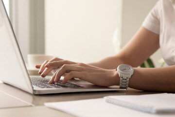 Womans hands typing laptop workplace